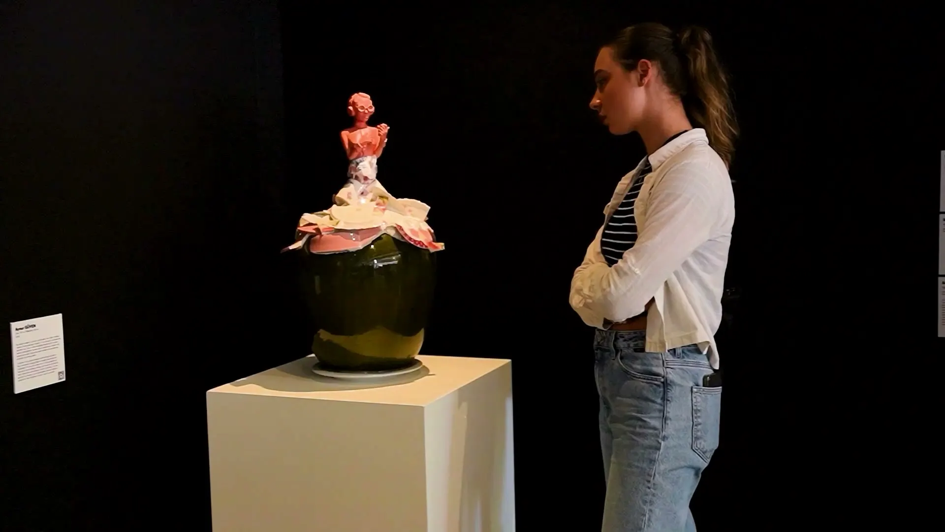 Ana sergide bir heykeli inceleyen ziyaretçi